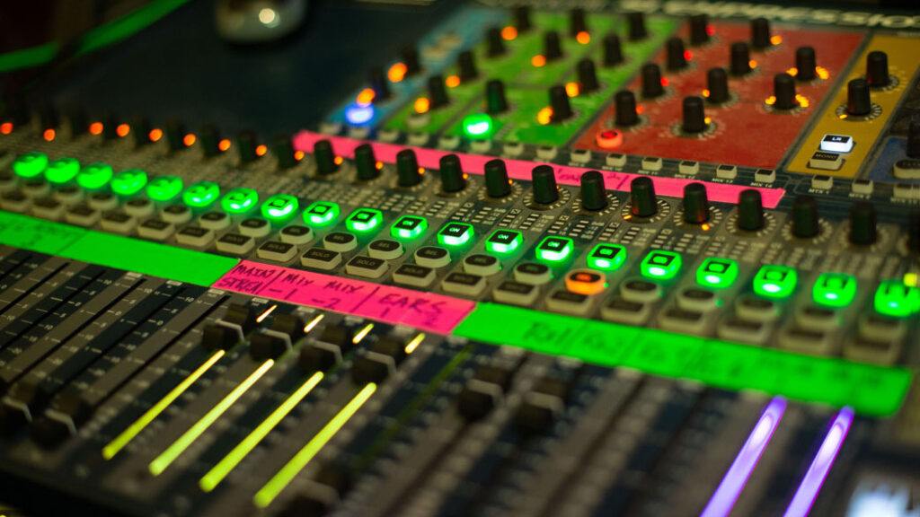 A shallow depth of field of a mixing desk with lots of buttons knobs and green lights