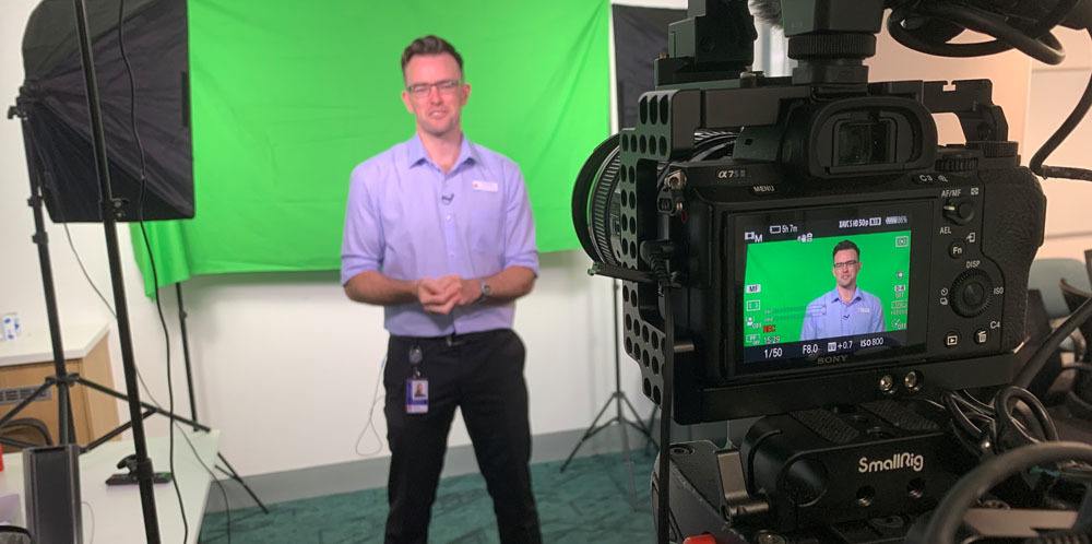 A man is being filmed in front of a green screen.
